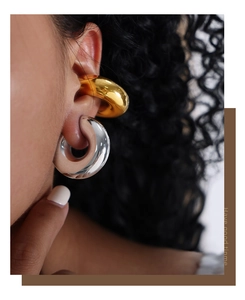 Close-up of thick chunky gold hoop earrings and transparent resin rings with metal core