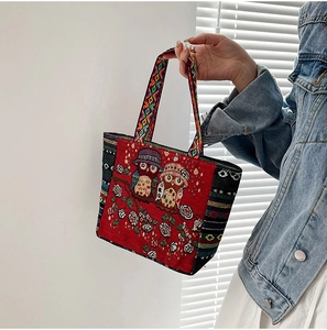 Close-up of red ethnic tote bag with owl embroidery and colorful braided handles
