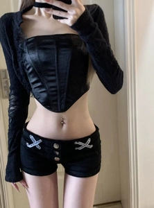 Detail von schwarzen Low-Rise-Jeans-Shorts mit Schnürung und dekorativem Banddesign