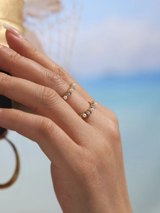 Close-up of elegant gold ring with pearls and zircons worn on model finger