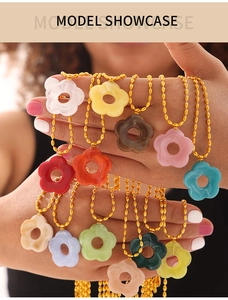 Close-up of colorful resin flower pendants on golden bead chains held by a model