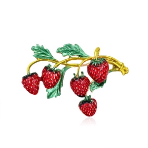 Detailed view of red strawberry brooch with green leaves and gold-tone metal texture