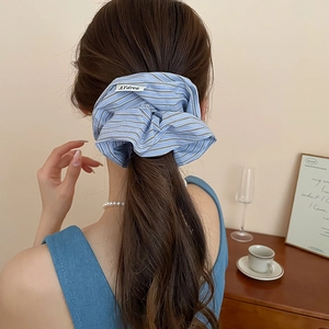 Detailed back view of a blue checkered fabric scrunchie on a ponytail with a sewn tag