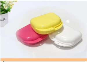 Three colorful dental retainer cases in yellow, pink and white with breathable vents