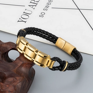 Men's double braided black leather bracelet with gold stainless steel clasp on a wooden base
