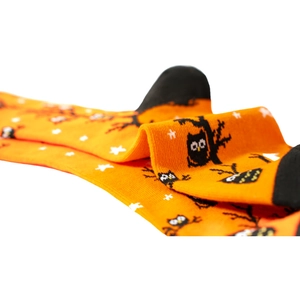 Macro di calze arancioni per Halloween con motivi a maglia di gufo nero e albero spoglio