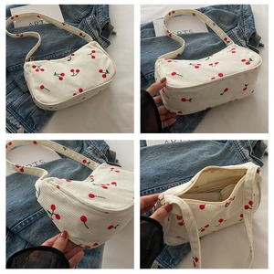 Multiple views of white corduroy underarm bag featuring red cherry prints and zip closure