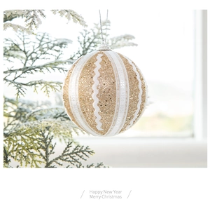 Detail einer 8cm goldenen Weihnachtskugel mit weißer Spitze an einem verschneiten Zweig