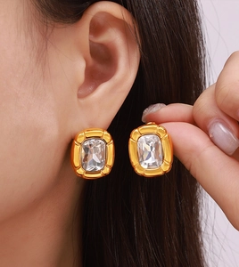 Close-up of model wearing gold rectangular earrings set with clear zircon stones