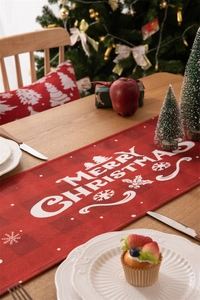 Detail of red Merry Christmas table runner with snowflakes on a festive wooden table