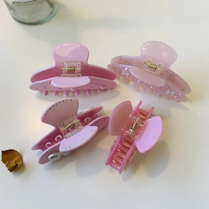 Détail d'un lot de quatre pinces à cheveux roses avec perles et strass sur table