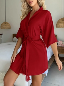 Détail du peignoir en satin bordeaux montrant la ceinture à pompons et le tissu soyeux