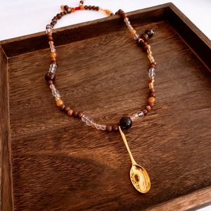 Détail du collier de perles vintage avec perles en verre et pendentif cuillère doré