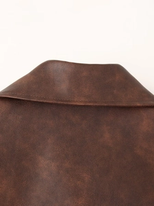 Gros plan du col d'une veste en similicuir marron foncé montrant la texture premium