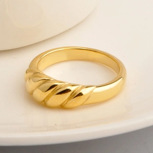 Goldener Croissant-Ring mit gedrehtem Gewindedesign auf einem Keramikteller