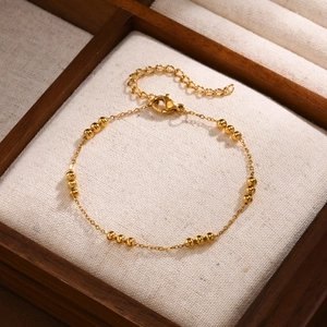 Detailed macro view of golden stainless steel bead bracelet with adjustable lobster clasp