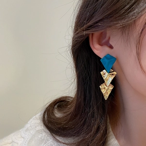 Three-tier geometric earrings with peacock blue matte and gold ripple metal textures on model