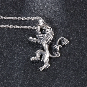 Macro shot of a silver lion head pendant with a twisted rope chain on a black surface