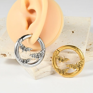Detail view of gold and silver hinged earrings featuring bat relief on ear model