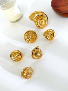 Detailed close-up of golden shell-shaped spiral earrings with elegant diamond accents