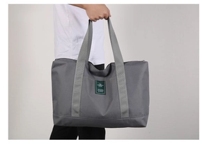 Gray large capacity canvas travel bag shown being carried by a model for size scale