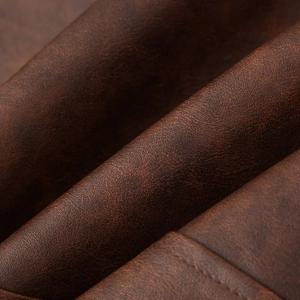 Détail de la texture cuir marron foncé sur un ensemble veste et jupe vintage