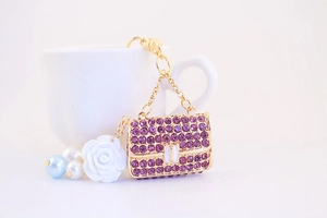Detailed macro shot of a gold handbag keychain encrusted with shiny purple rhinestones