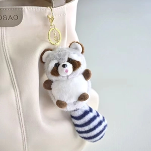 Detail van een schattige pluche wasbeer sleutelhanger met gestreepte staart op tas