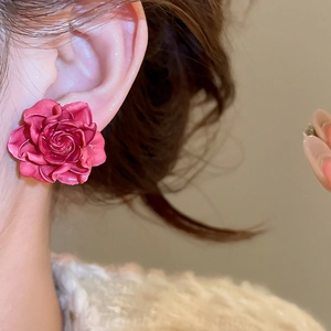 Detailed view of dark pink resin rose flower earrings on model showcasing 3D petal texture