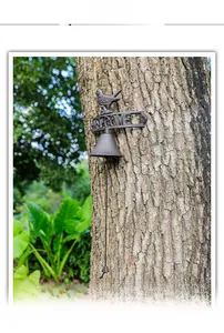 Detail of vintage cast iron welcome bell with bird ornament on rustic tree trunk