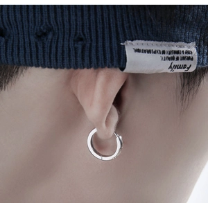 Close-up of minimalist silver hoop earring worn on ear with blue knit beanie background