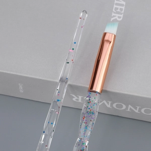 Detail of angled brow brush with crystal handle and rose gold ferrule on a book