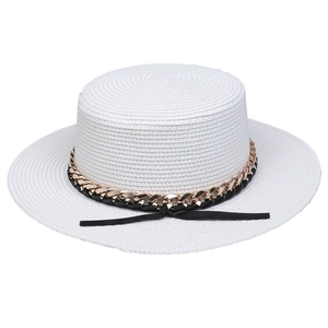 Detail of white straw sun hat featuring a black ribbon and gold metal chain accent