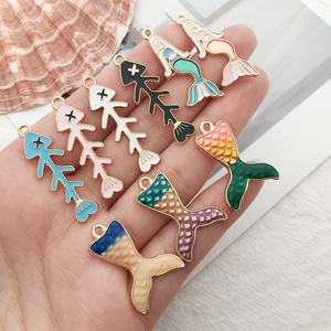 Enamel mermaid and fishbone alloy pendants in various colors shown on hand for DIY