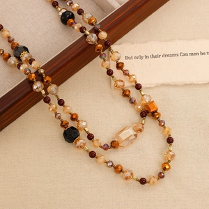 Detail of layered bohemian beaded necklace with champagne crystals and wooden tray background