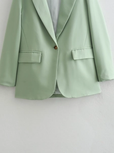 Detail shot of light green long-sleeved blazer featuring classic lapels and single button