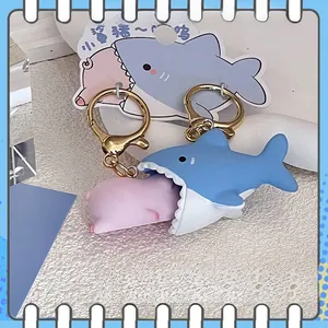 Detail of shark and pig cartoon couple keychains with metallic gold rings on a display card