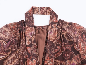 Detailed view of the brown paisley print and halter neck design on a lightweight chiffon dress
