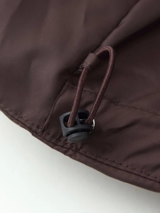 Detail of adjustable drawstring hem with toggle on chocolate brown hooded jacket