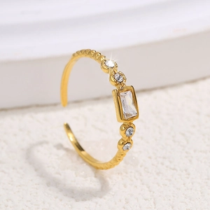 Detail of adjustable gold ring with emerald cut center stone and side zirconias