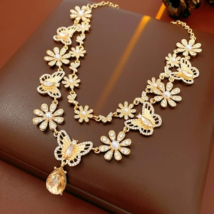 Détail du collier vintage doré avec breloques fleurs en résine, papillons et perles