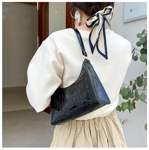 Detailed back view of a black crocodile pattern half-moon shoulder bag on a model