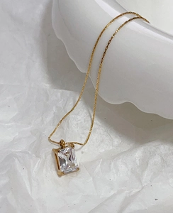 Macro detail of rectangle emerald-cut green zircon pendant on 18k gold plated chain