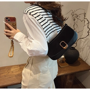 Detail showing a black leather underarm bag with a golden buckle on a model