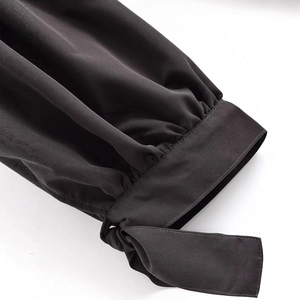 Close-up of stylish dark grey lantern pants with bow tie-knot detail and pleated cuff