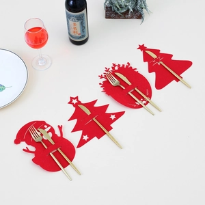 Macro detail of red felt Christmas cutlery holders with golden knives and forks on a table