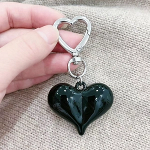 Deep green heart pendant keychain with silver heart-shaped clasp held against knit fabric