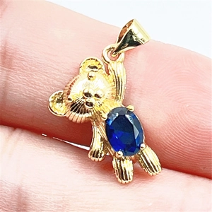 Vue macro du pendentif ours doré avec incrustation de pierre ovale bleu foncé