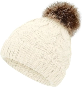 Detailed macro view of cream knitted hat with cable patterns and brown fur pompom