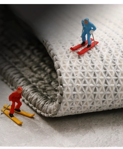 Macro detail of grey woven door mat with white non-slip geometric texture backing